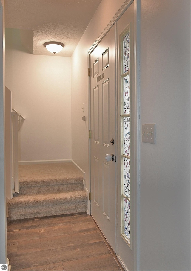 entryway with stairway, baseboards, wood finished floors, and a textured ceiling