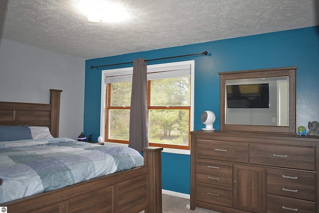 carpeted bedroom featuring baseboards and a textured ceiling