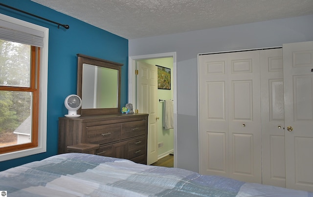 bedroom with ensuite bath, a textured ceiling, and a closet