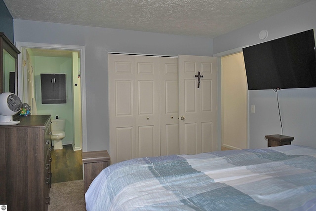 bedroom featuring ensuite bath, a textured ceiling, and a closet