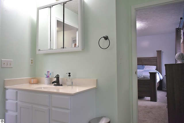 ensuite bathroom featuring a textured ceiling, vanity, and connected bathroom