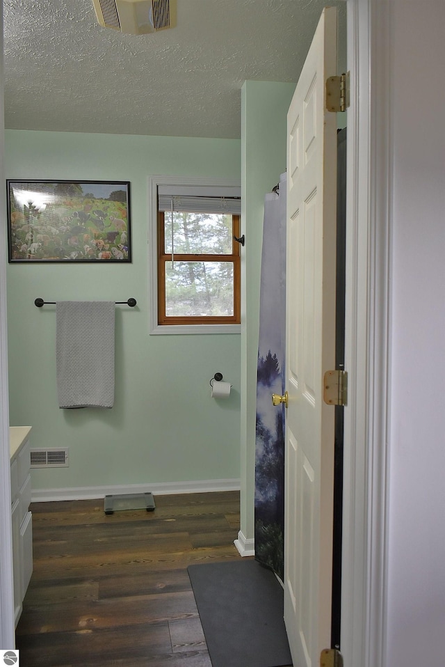 bathroom with baseboards, wood finished floors, visible vents, and a textured ceiling