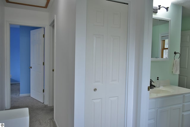 hallway featuring baseboards, carpet flooring, and a sink