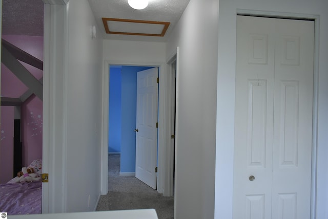 hallway with attic access and carpet