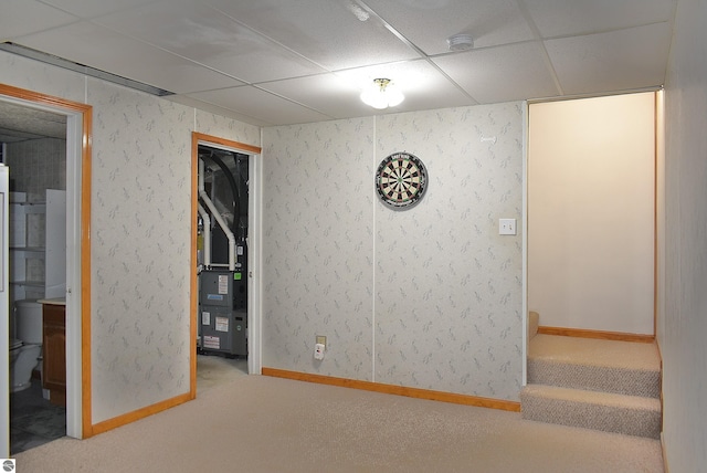 interior space with carpet flooring, a drop ceiling, and baseboards