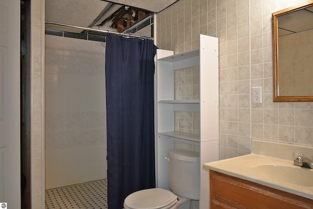 bathroom featuring tile walls, toilet, vanity, and a tile shower