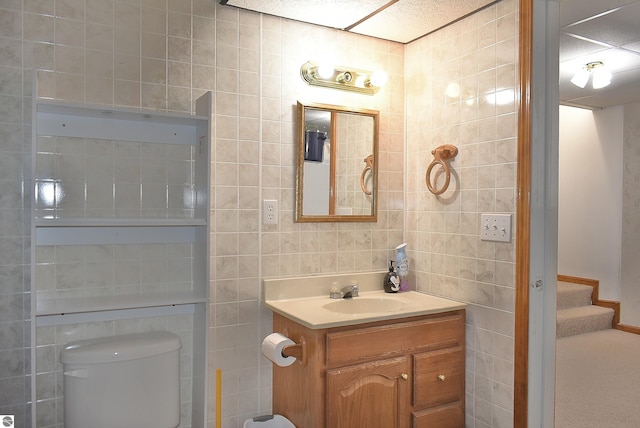 bathroom with toilet, vanity, and tile walls