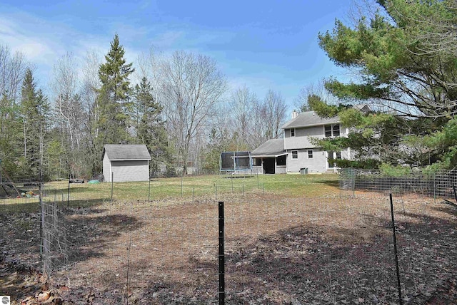 view of yard with fence, an outdoor structure, a storage shed, and a trampoline