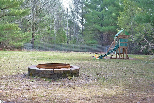 view of yard featuring a fire pit, a playground, and fence