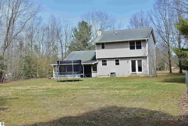 back of house with a chimney, entry steps, and a lawn