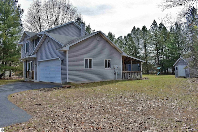 view of side of property with a chimney, driveway, a playground, and a garage
