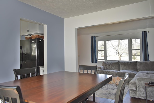 dining space with a textured ceiling and dark wood finished floors