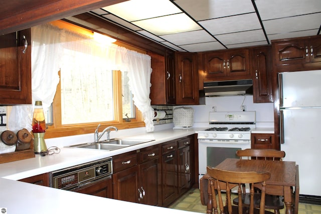 kitchen featuring under cabinet range hood, light floors, light countertops, a sink, and white appliances
