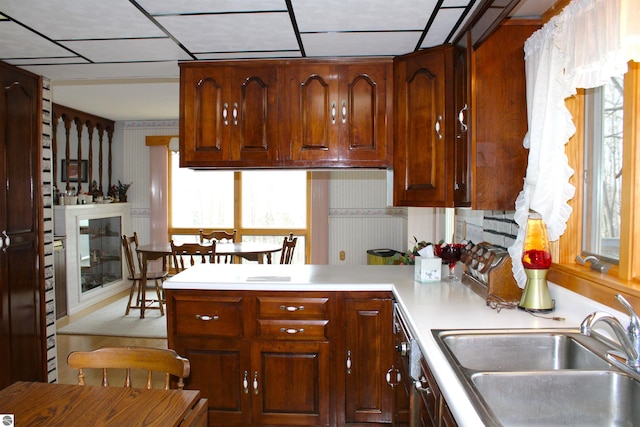 kitchen with a peninsula, light countertops, a sink, and a healthy amount of sunlight