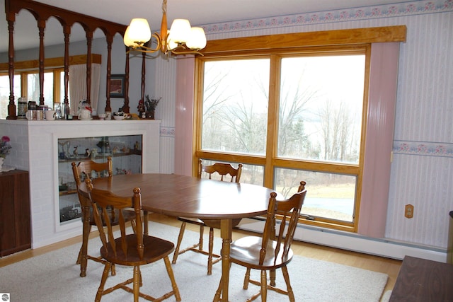 dining room with a baseboard radiator, wood finished floors, a chandelier, and wallpapered walls