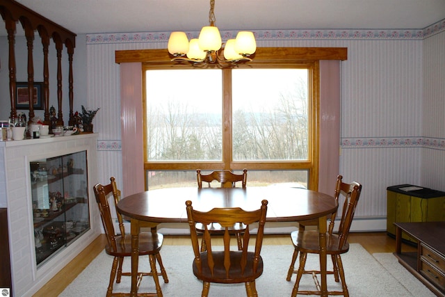 dining space with a chandelier, wallpapered walls, wood finished floors, and baseboard heating