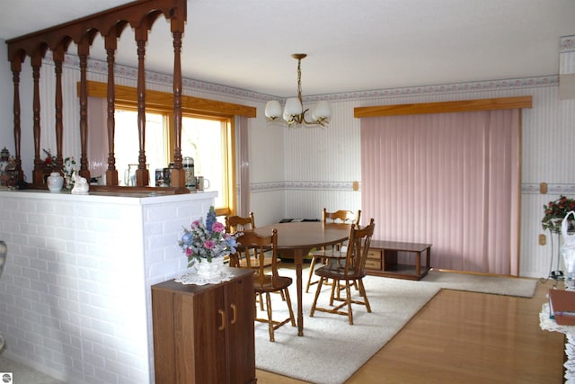 dining room featuring a chandelier, wallpapered walls, wood finished floors, and wainscoting