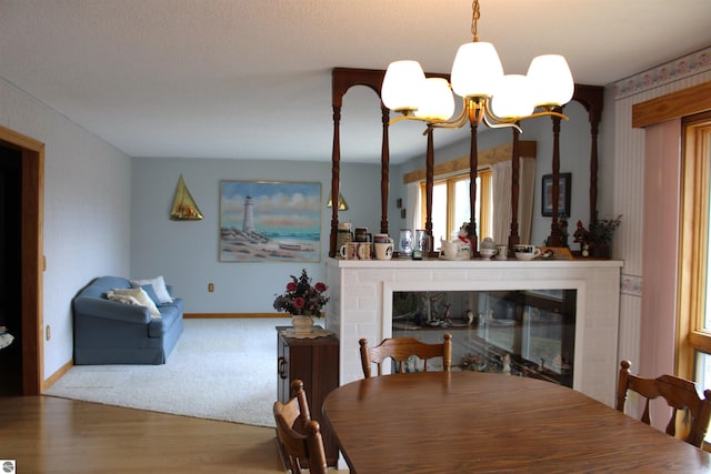 dining room featuring a glass covered fireplace, wood finished floors, baseboards, and a notable chandelier