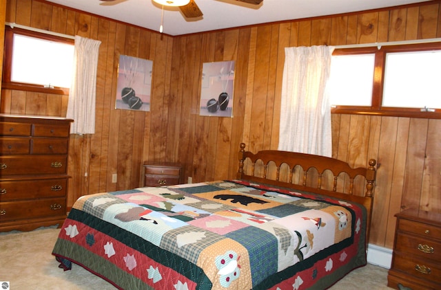 carpeted bedroom with baseboard heating, wooden walls, and a ceiling fan