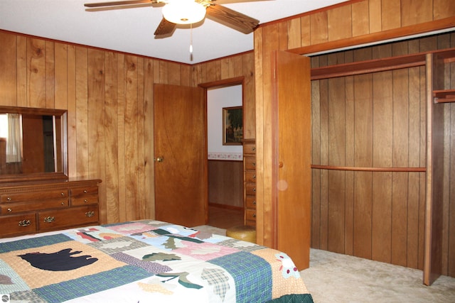 carpeted bedroom with wooden walls, a closet, and ceiling fan