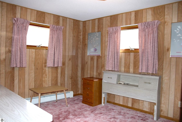 bedroom featuring baseboard heating, wood walls, carpet floors, and multiple windows