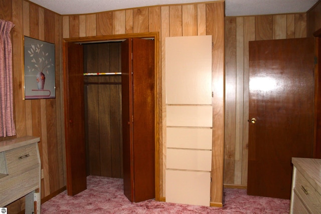 unfurnished bedroom with light colored carpet, wooden walls, and a closet