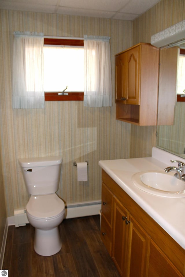 bathroom featuring wallpapered walls, wood finished floors, toilet, a baseboard heating unit, and baseboards