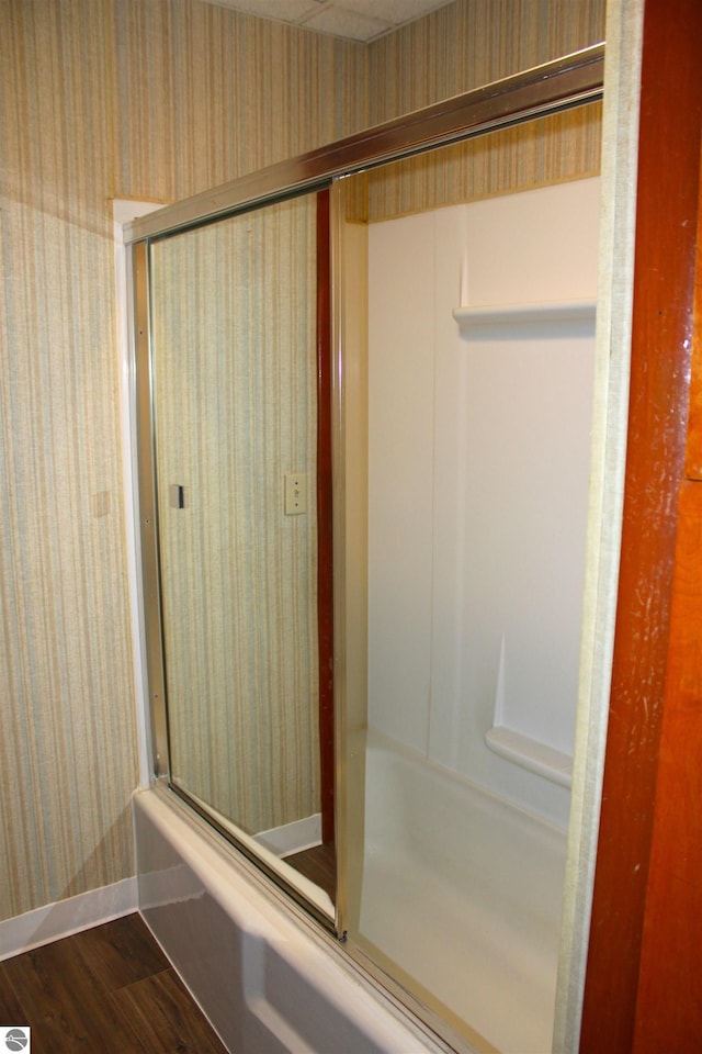 bathroom featuring wallpapered walls, wood finished floors, an enclosed shower, and baseboards