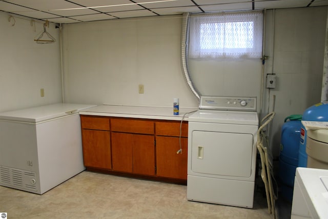 laundry room with washing machine and clothes dryer, light floors, and cabinet space