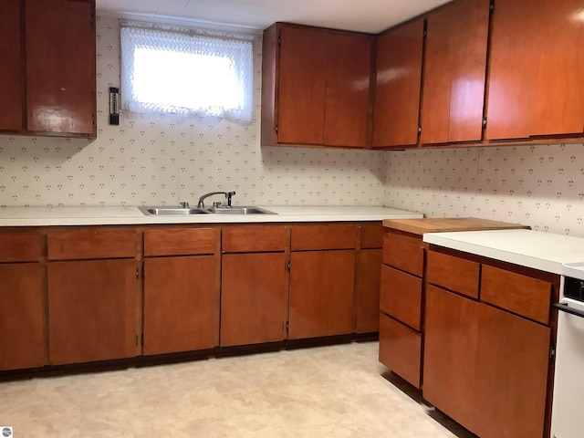 kitchen featuring light floors, wallpapered walls, light countertops, and a sink