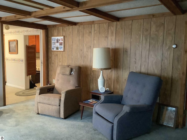 sitting room with beamed ceiling, carpet flooring, and wooden walls