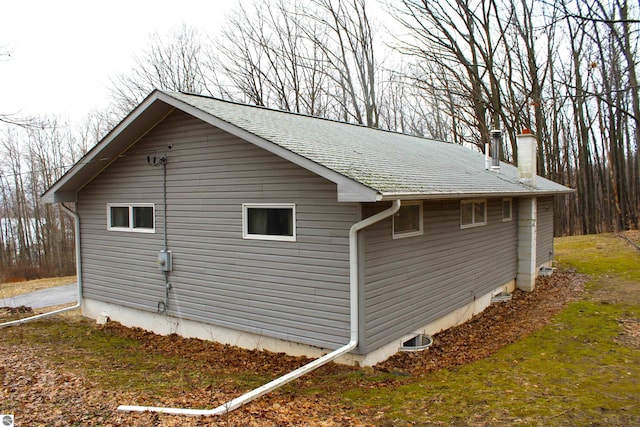view of side of home featuring a shingled roof and a chimney