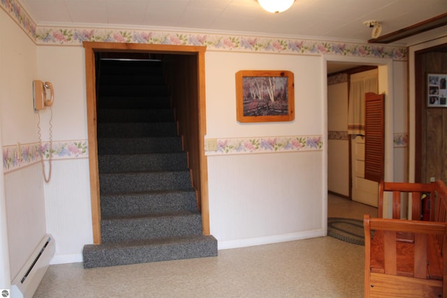 stairway featuring a baseboard heating unit, wainscoting, and ornamental molding