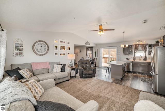 living area with lofted ceiling, dark wood-style floors, and ceiling fan with notable chandelier