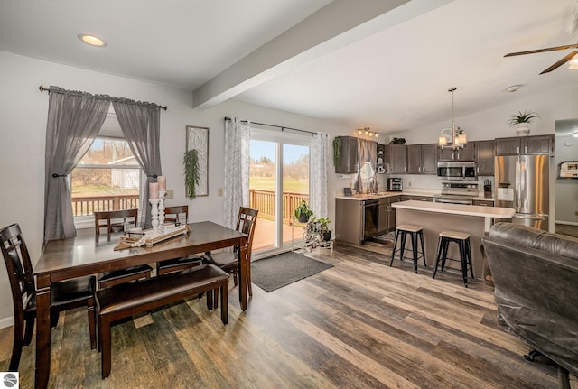 dining area with ceiling fan with notable chandelier, lofted ceiling with beams, wood finished floors, and a wealth of natural light
