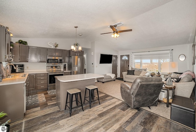 living area with vaulted ceiling, dark wood-type flooring, a textured ceiling, and ceiling fan with notable chandelier