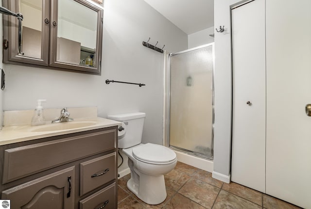 bathroom featuring a shower stall, toilet, vanity, and baseboards