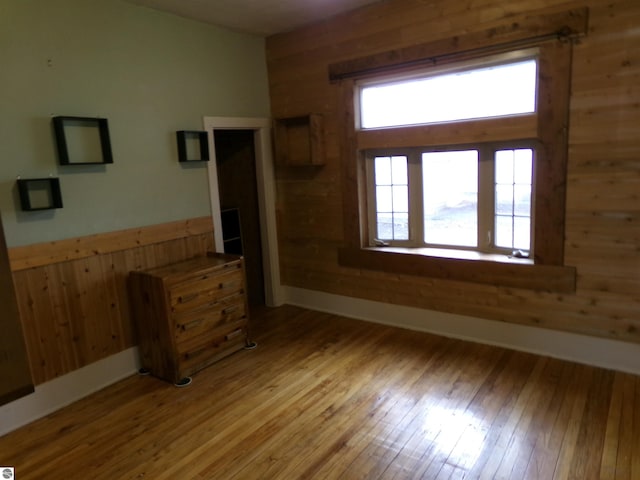 116 N Main St, Saint Louis, MI 48880 - unfurnished living room with wainscoting, wood walls, light wood finished floors, and baseboards