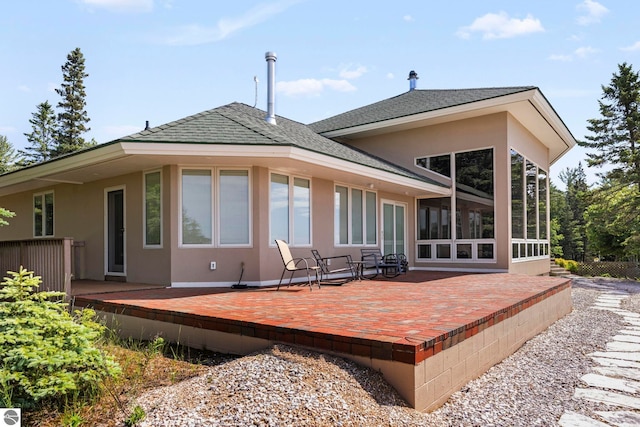5343 Michibay Dr, Manistique, MI 49854 - back of house featuring a patio, stucco siding, a wooden deck, roof with shingles, and a sunroom