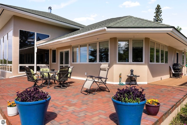 5343 Michibay Dr, Manistique, MI 49854 - back of property with a shingled roof, a patio, and stucco siding
