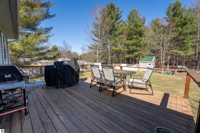 1294 Fisher Rd, Traverse City, MI 49685 - wooden deck featuring a grill, a storage shed, outdoor dining space, an outdoor structure, and a lawn