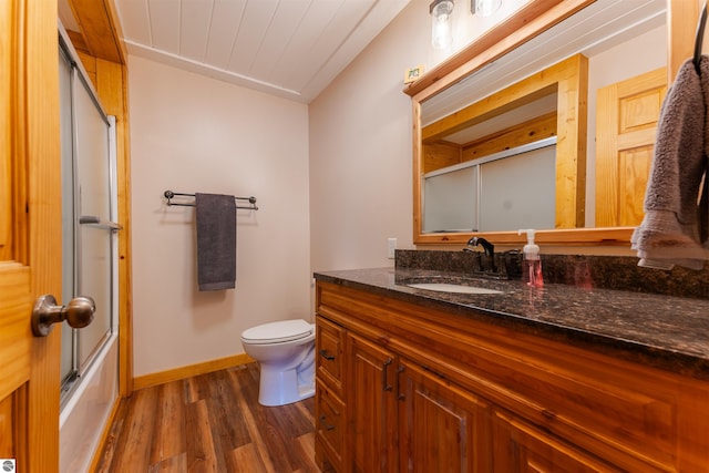 1294 Fisher Rd, Traverse City, MI 49685 - full bath with wood finished floors, vanity, baseboards, toilet, and shower / bath combination with glass door