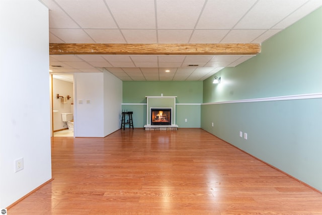 1294 Fisher Rd, Traverse City, MI 49685 - unfurnished living room with visible vents, a glass covered fireplace, a paneled ceiling, and wood finished floors