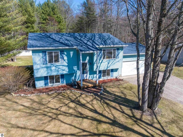 1294 Fisher Rd, Traverse City, MI 49685 - bi-level home with roof with shingles, a detached garage, and a front yard