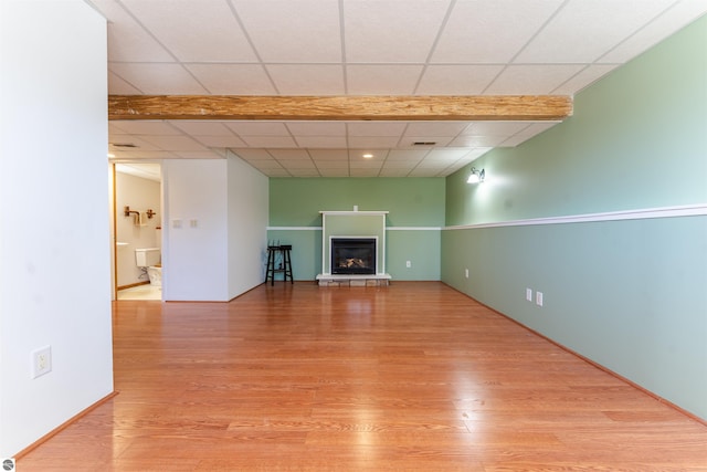 1294 Fisher Rd, Traverse City, MI 49685 - unfurnished living room featuring visible vents, a glass covered fireplace, wood finished floors, and a paneled ceiling