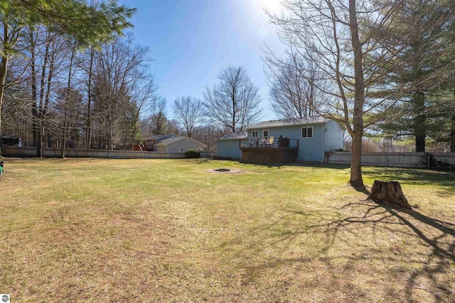 1294 Fisher Rd, Traverse City, MI 49685 - view of yard featuring a wooden deck, a fenced backyard, and an outdoor fire pit