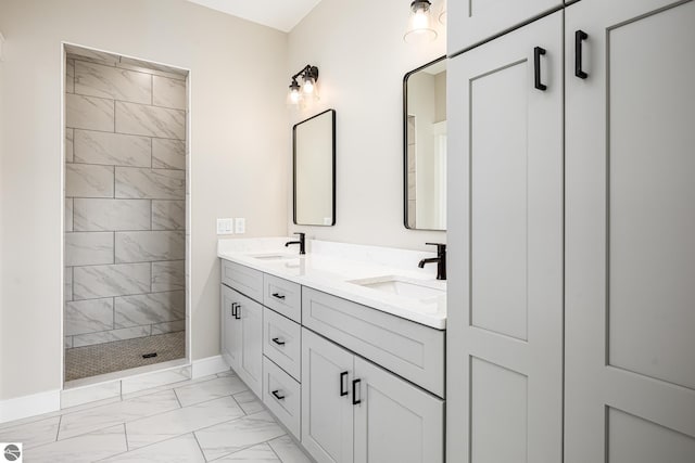 bathroom with baseboards, marble finish floor, a sink, and tiled shower