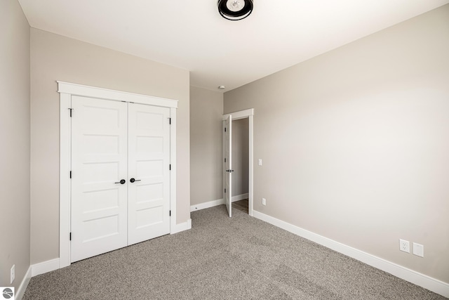 unfurnished bedroom with light carpet, baseboards, and a closet