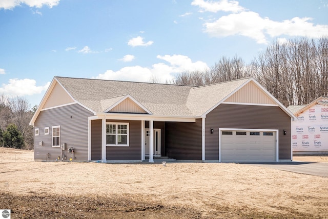 view of front of property with driveway, covered porch, a shingled roof, and a garage