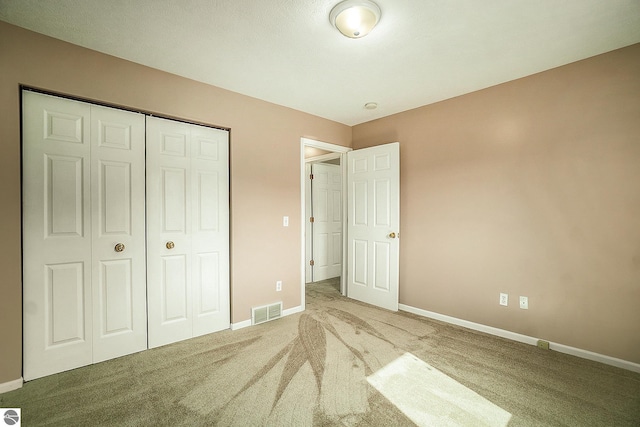 unfurnished bedroom featuring baseboards, carpet flooring, visible vents, and a closet